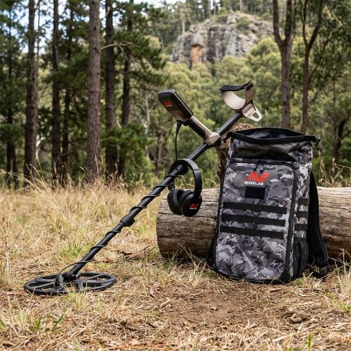 Metal detector and accessories on a grassy field with forest in the background