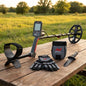Metal detector and accessories on picnic table in grassy field