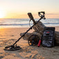 Metal detector and backpack on a beach with sunset in the background